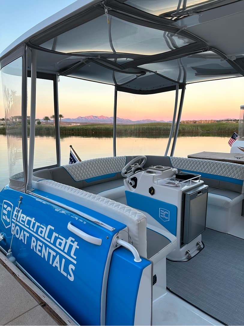 ElectraCraft 162TR cockpit viewed from the port side, showing seating, helm, console, canopy, and lake beyond