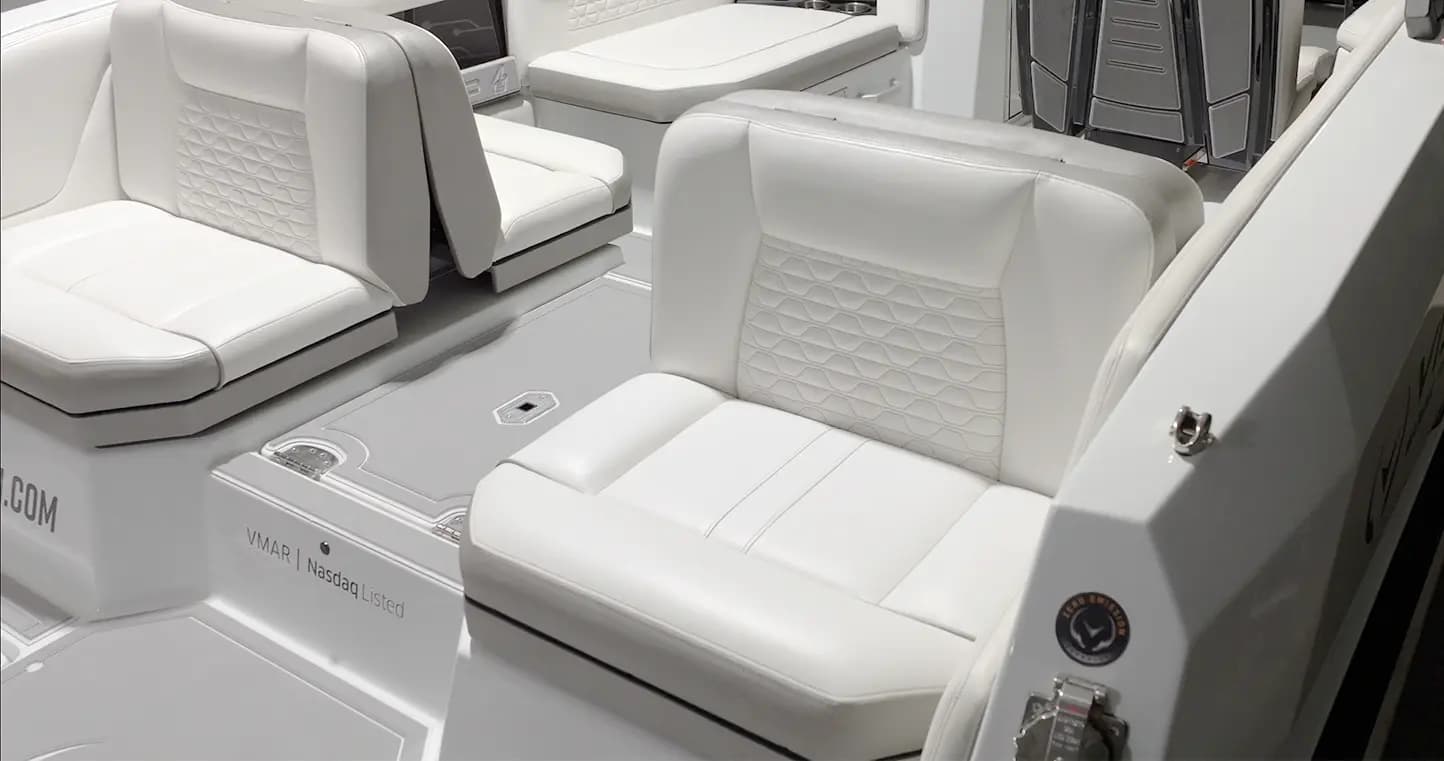 View from the side into a boat (2026 Vision Marine SPECTR) cockpit with white upholstered seating, a center console, and visible deck controls.