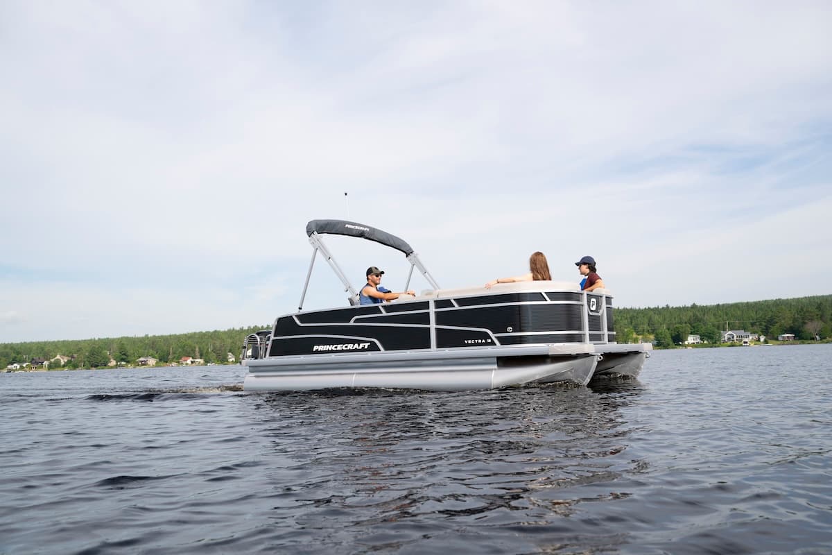 2026 Princecraft Vectra 19 L pontoon boat viewed from the side on a lake, with a bimini top and people aboard