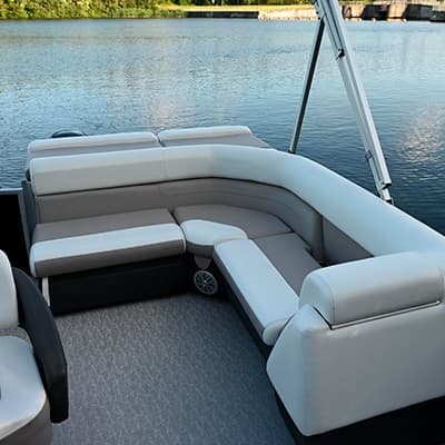View from the stern into the cockpit of a pontoon boat (2026 Princecraft Vectra 19 L), showing wraparound seating, cushioned benches, and textured flooring.