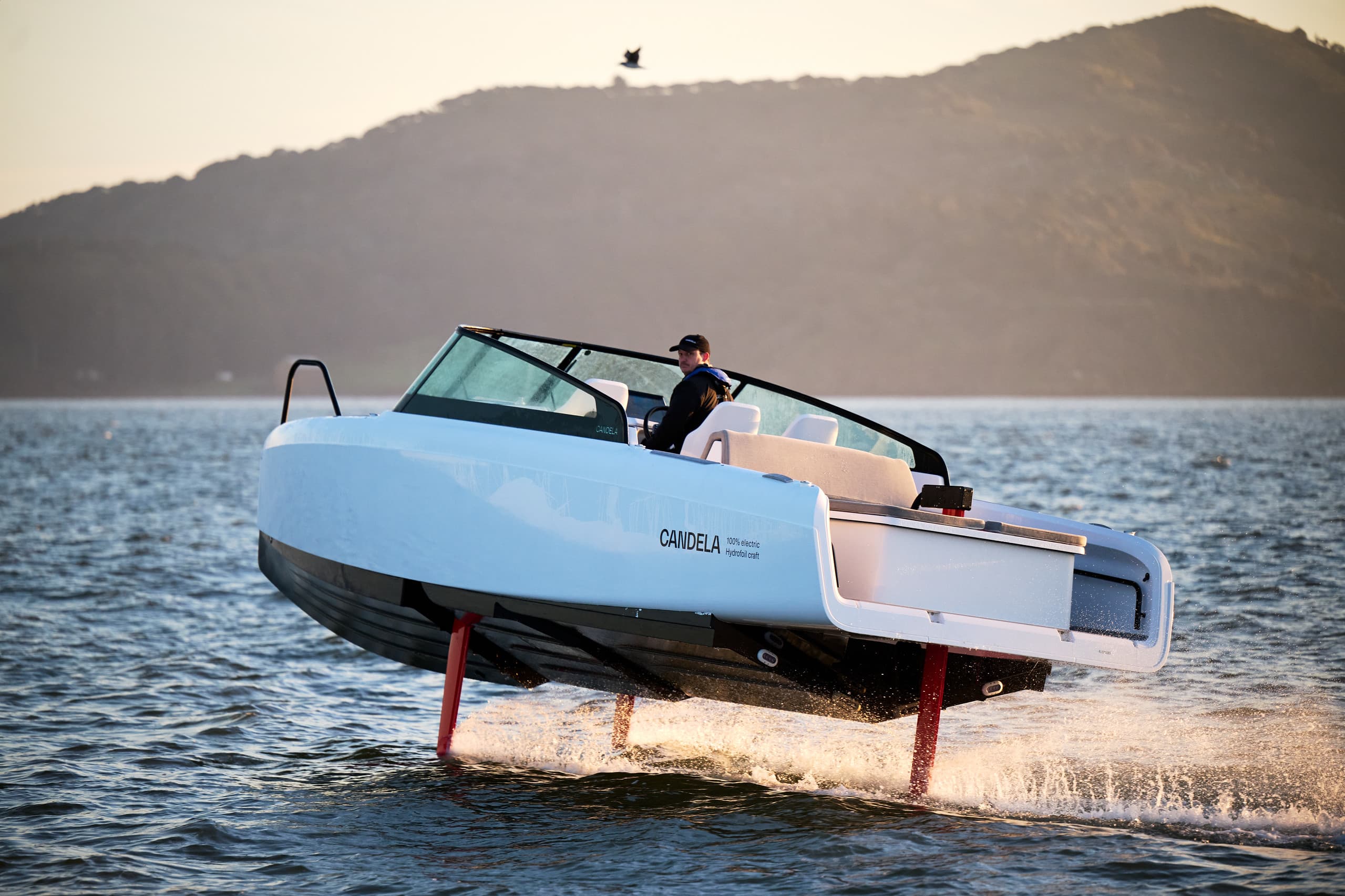 Candela C-8 hydrofoil boat viewed from the side, skimming above the water with its foils visible.