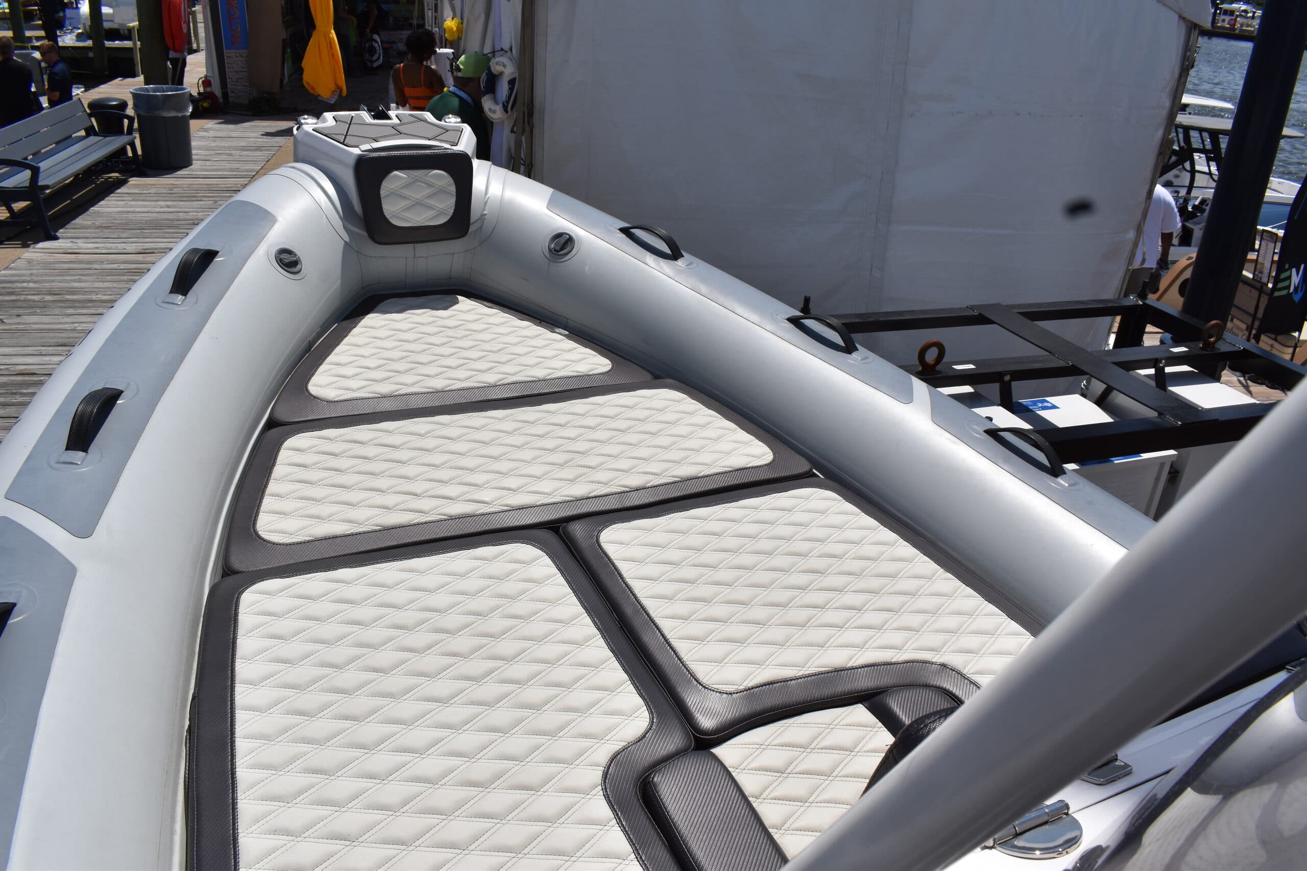 Highfield Sport 660 inflatable boat bow with cushioned deck, grab handles, and console visible at a marina dock.