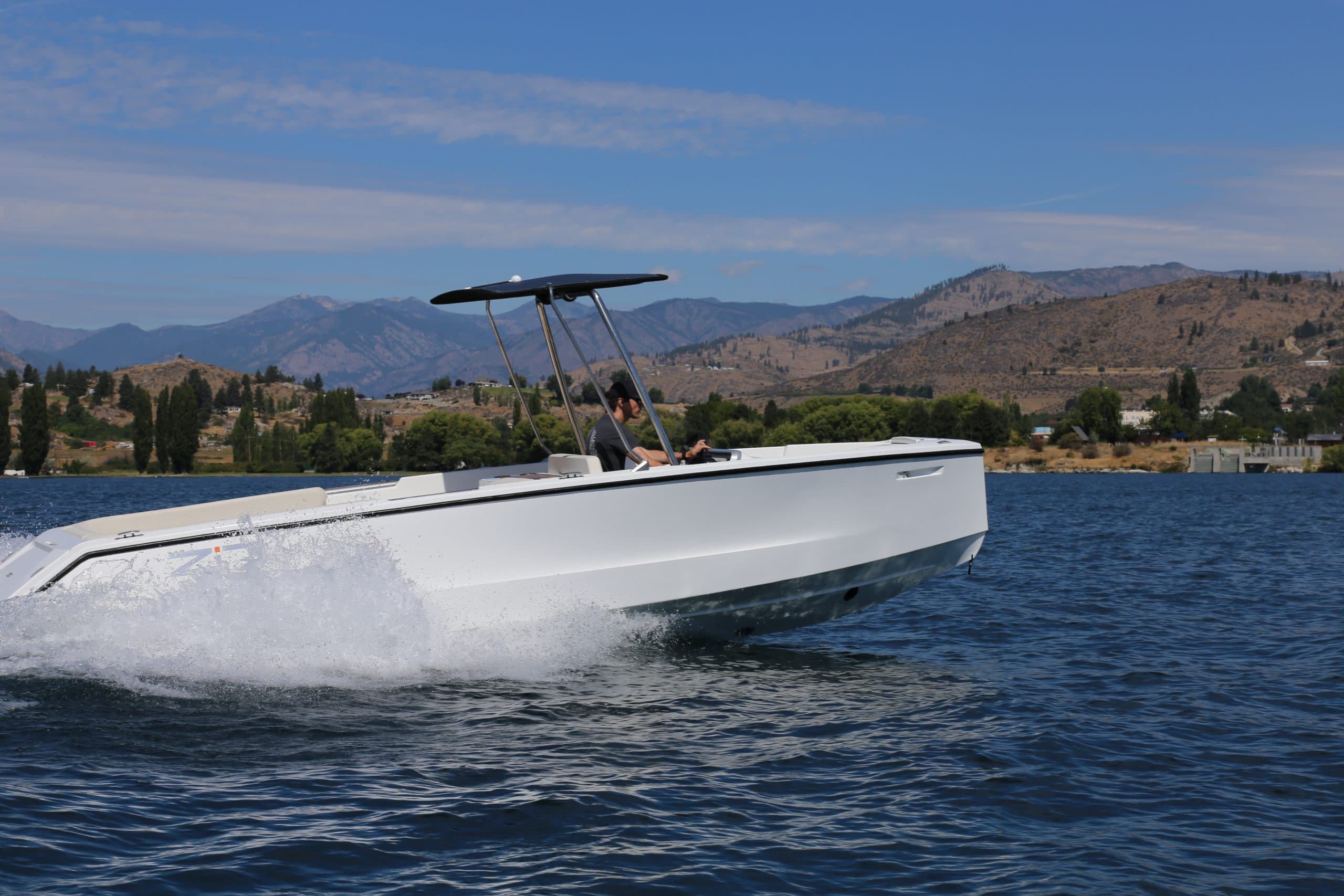 Zin Boats Z7 speeding across a lake, viewed from the starboard side with the bow raised and wake spraying behind.