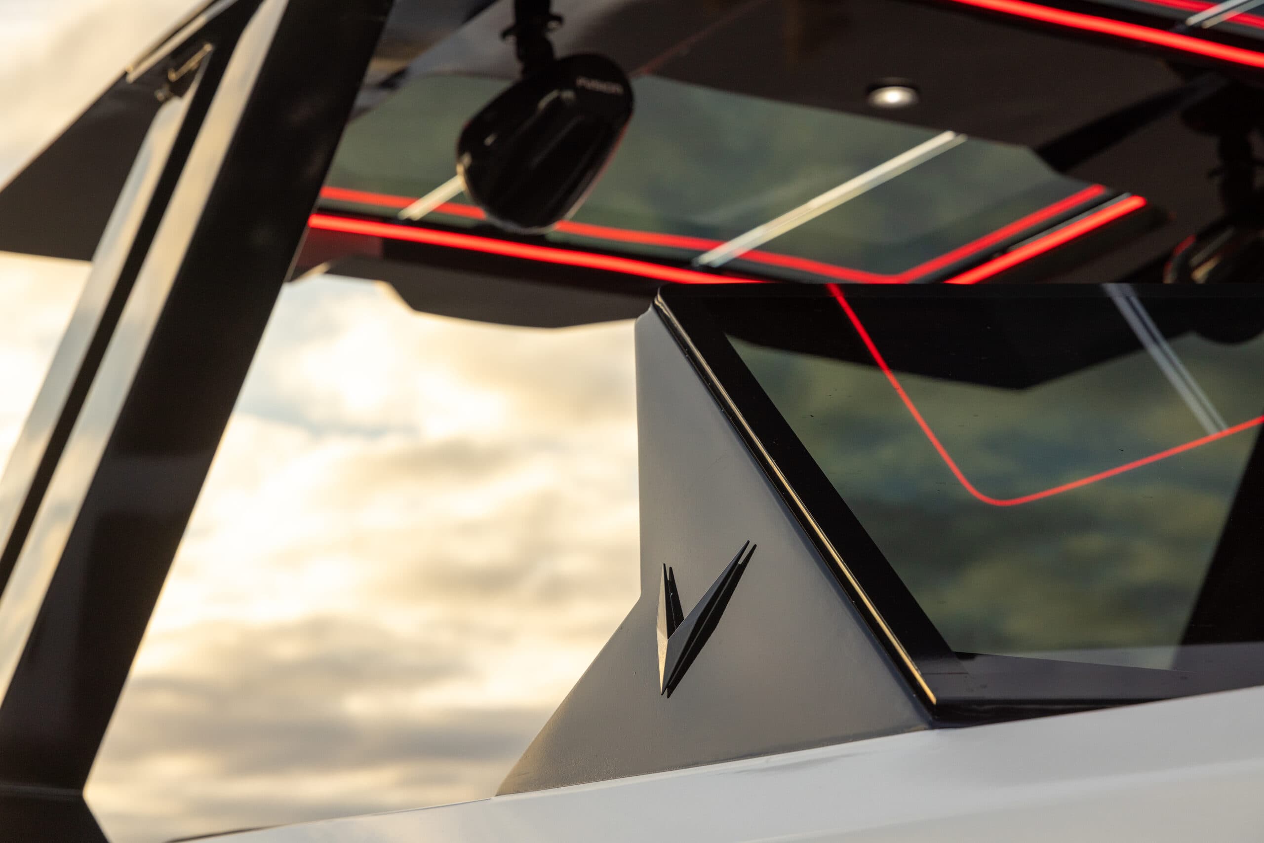Close-up of the boat’s windshield and roof from the port side, showing angular glazing and red interior accent lighting (2026 Voltaic AEW24).