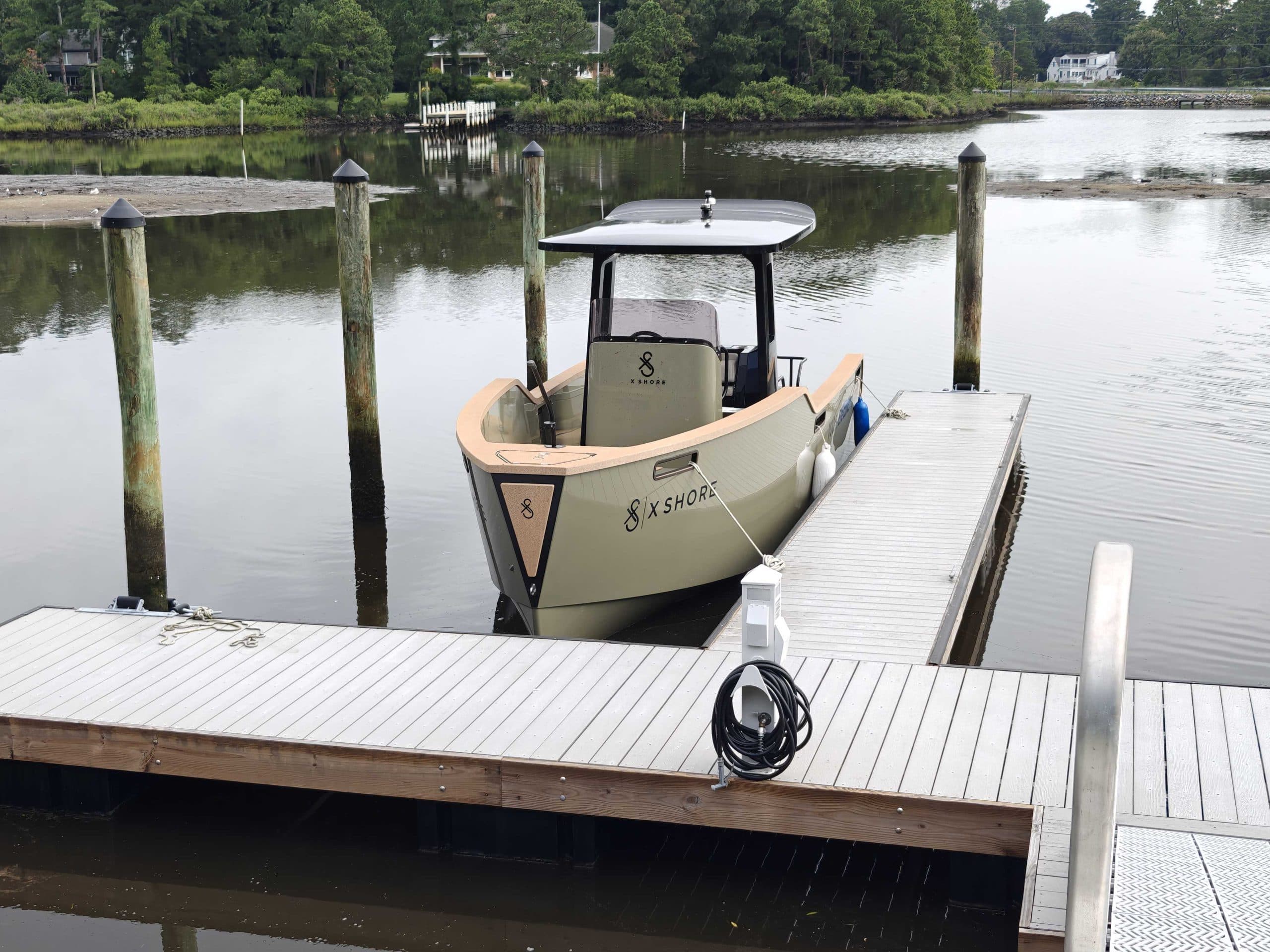 X Shore Eelex boat moored at a dock, viewed from the front-left side.