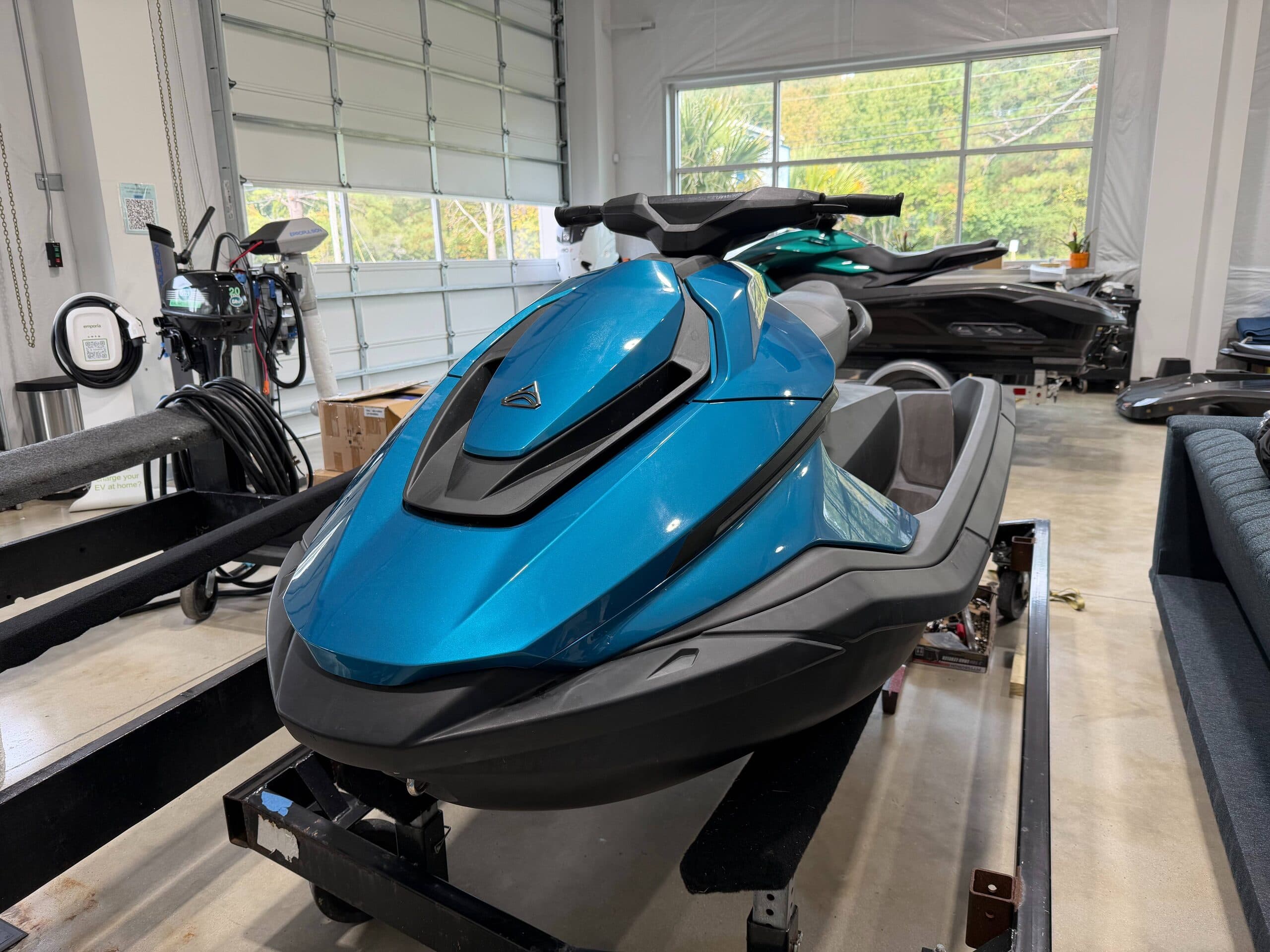 Front three-quarter view of a blue personal watercraft (Taiga Orca P2) on a trailer inside a showroom.