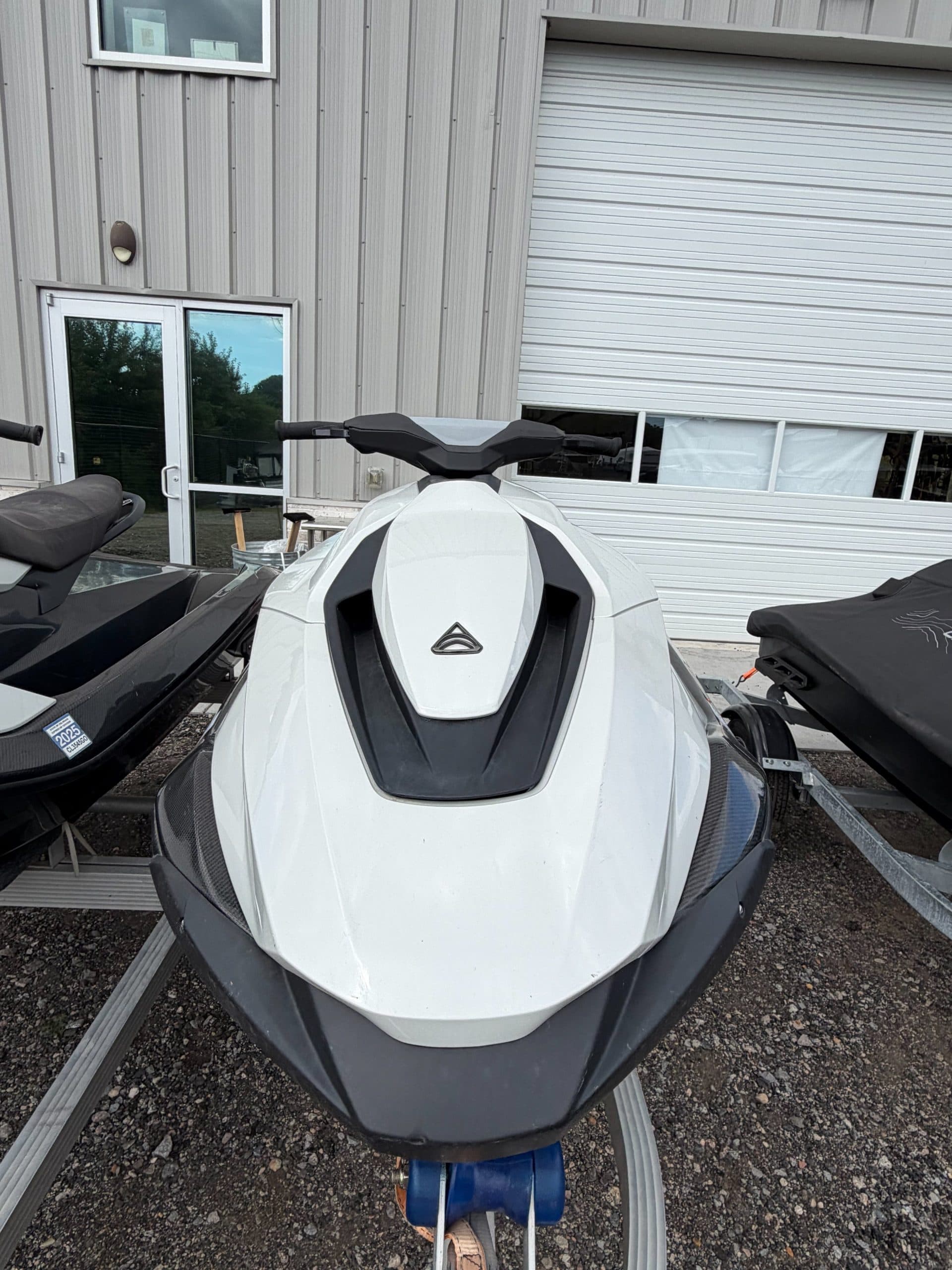 Front view of a white personal watercraft on a trailer, showing the bow, handlebars, and seat area.